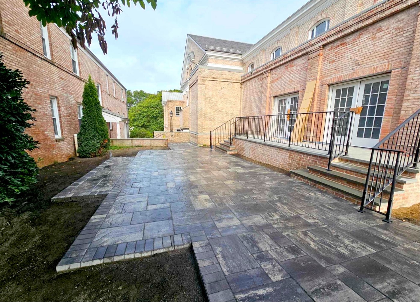 Large stamped paver courtyard between two brick buildings with iron railings
